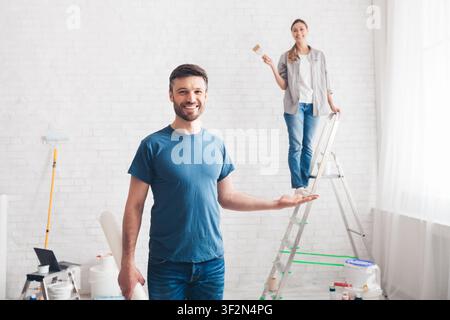 Man holding wife on palm while she painting walls Stock Photo