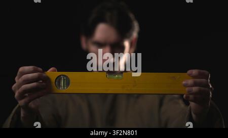 Man holding a yellow spirit level in a dark studio Stock Photo