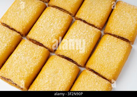 Fig roll bar, square sugar cookies with fruit filling. Taiwanese pineapple cake, brown rectangular strudel biscuits, sweet apple roll pastry on white Stock Photo
