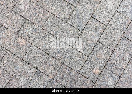 Herringbone granite pavers create a textured urban pavement pattern and close-up background, highlighting geometric lines, stone surface details and t Stock Photo
