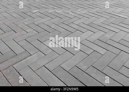 Herringbone pattern of gray concrete pavers forming a clean, geometric outdoor walkway. Close-up view emphasizes texture, repetition and modern hardsc Stock Photo