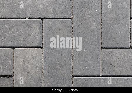 Detailed close-up top view of gray concrete pavers arranged in a geometric pattern on an urban pavement surface. Subtle texture and joints create a ne Stock Photo