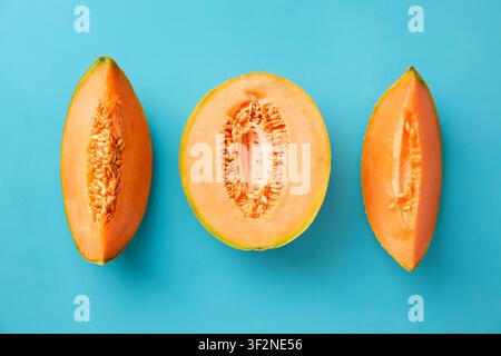 Ripe cantaloupe melon cut into slices on blue background Stock Photo