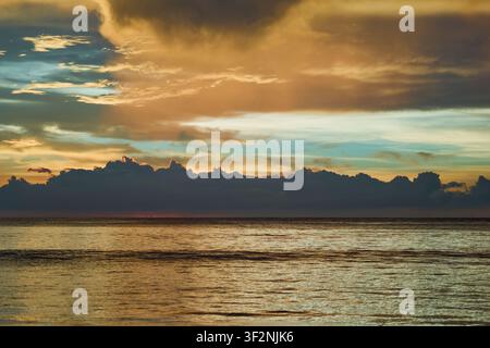 Dramatic Golden Sunset Over Calm Ocean Horizon with Majestic Storm Clouds and Reflections. Stock Photo