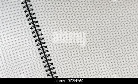 Open spiral bound notebook with blank squared graph paper viewed from above. Minimal stationery background with copy space for notes, mathematics Stock Photo