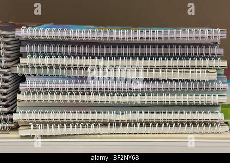 Spiral notebook stack. Pile of spiral notebooks stacked on desk with visible pages and bindings for school, office, study storage. Back to school Stock Photo