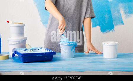 Paint on table. Girl dips a brush in a bucket. Stock Photo