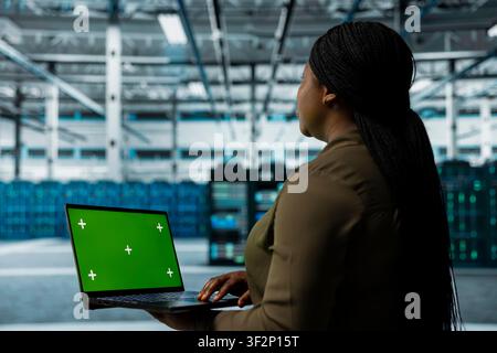 Data center engineer monitors components for potential failures using isolated screen laptop, improving system stability. Server hub expert uses mockup notebook to configure settings, increases uptime Stock Photo