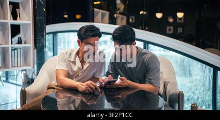 Gay couple enjoying mobile phone content together, sharing online moments Stock Photo