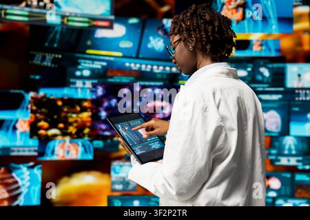 Biomedical engineer studying human body using tablet app, comping up with medical innovations. Scientist looking at human organs on device screen, doing analysis and comparisons Stock Photo