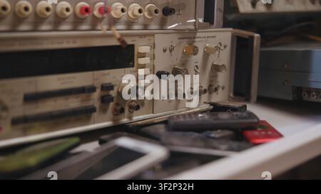 Vintage rack-mounted electronics test panel seen from low angle with rotary knobs, toggle switches, connectors, stacked pushbuttons, and worn metal Stock Photo