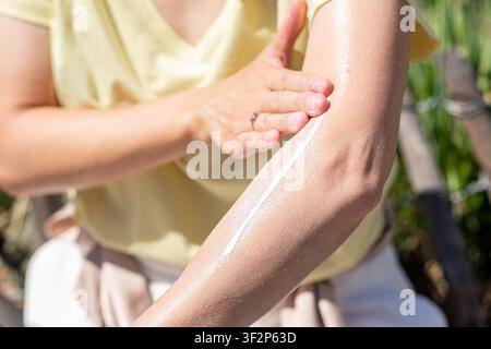Woman applying sunscreen on her arm for sun protection Stock Photo