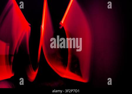 Abstract composition with red light reflections and glowing shapes on a dark background creating a dramatic visual effect. Stock Photo
