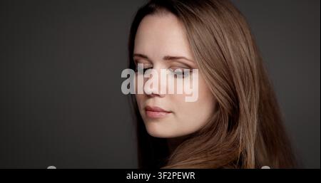 Young woman with natural make up and long hair contemplating with closed eyes Stock Photo
