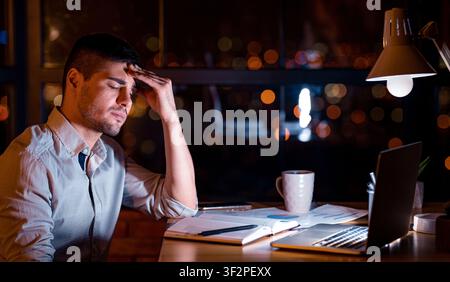 Tired Manager At Laptop Touching Forehead Working Late In Office Stock Photo