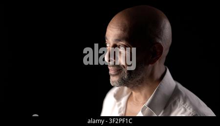 Side view of a bald man with a beard looking upwards with a hopeful expression Stock Photo