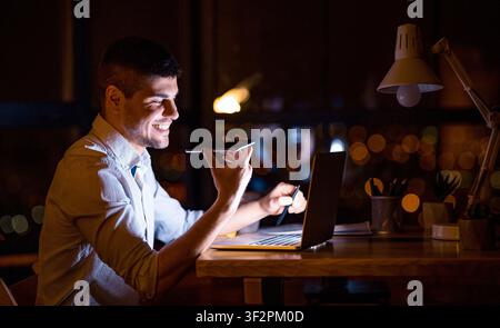 Young Entrepreneur Using Voice Assistant Working On Laptop In Office Stock Photo