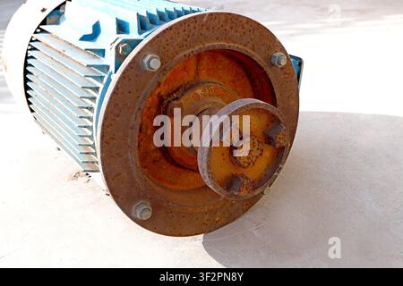 An old blue industrial electric motor covered with rust and wear marks, with peeling paint and corroded metal parts, showing the vicissitudes of long- Stock Photo
