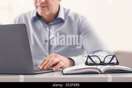 Unrecognizable middle aged man using laptop at home Stock Photo