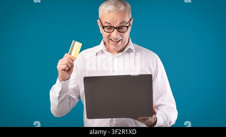 Happy mature man holding credit card and computer Stock Photo