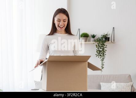Woman unboxing cardboard box with protective foam pads inside Stock Photo