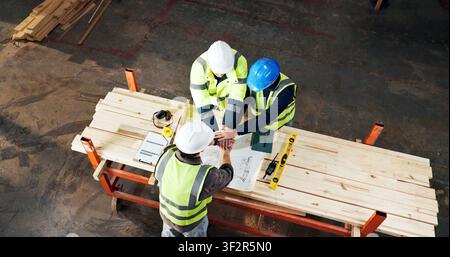 Meeting, blueprint and men with hand stack for carpentry, construction project and agreement. Warehouse, above and people with teamwork for renovation Stock Photo
