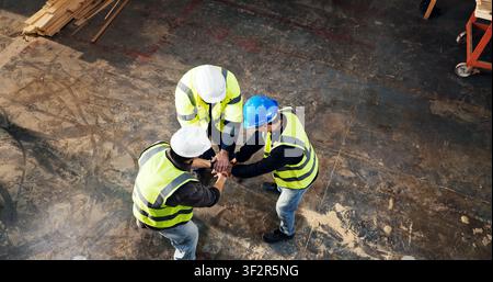 Above, success and men with hand stack for carpentry, construction project and agreement. Happy, teamwork and people with support for renovation Stock Photo