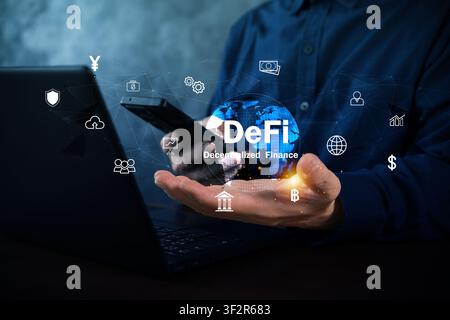 A business user holds a glowing DeFi globe while using a smartphone and laptop, illustrating blockchain finance, digital assets, secure payments, and Stock Photo
