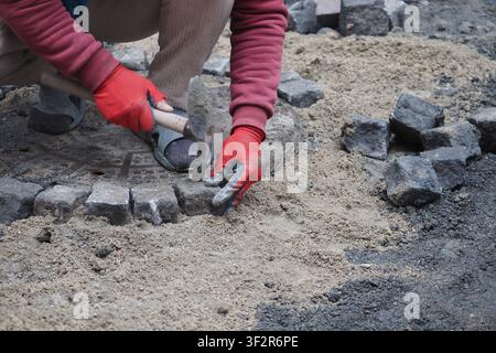 Person laying bricks on a construction site in daylight Stock Photo