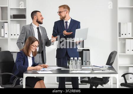 Business people collaborating in a modern office, discussing project strategy and financial data with a laptop Stock Photo