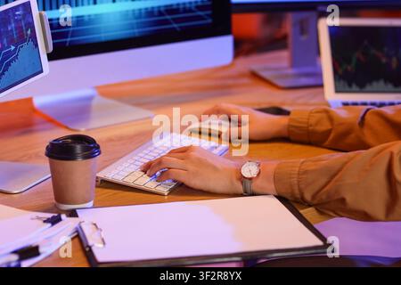 Person working on computer with multiple screens displaying financial graphs and data in a modern office setting, Essence of business analysis, online Stock Photo