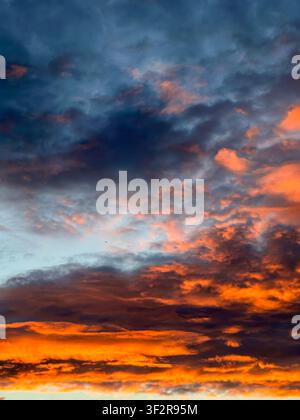 Vivid orange and blue sunset clouds create a dramatic evening sky with rich textures and striking natural light. Ideal for backgrounds, weather concep Stock Photo