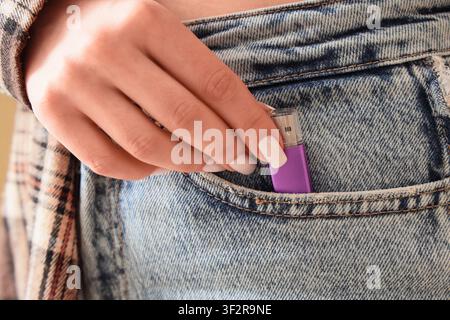 Womans hand placing a purple usb flash drive into the front pocket of blue denim jeans, data storage and portability Stock Photo