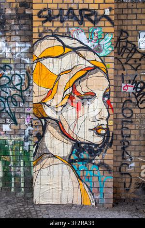 Cut-out street art poster by El Bocho on yellow brick wall in Mitte district of Berlin, Germany Stock Photo