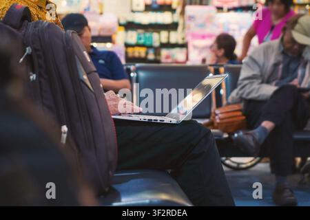 close up of man working on laptop computer while waiting in the airport terminal Stock Photo