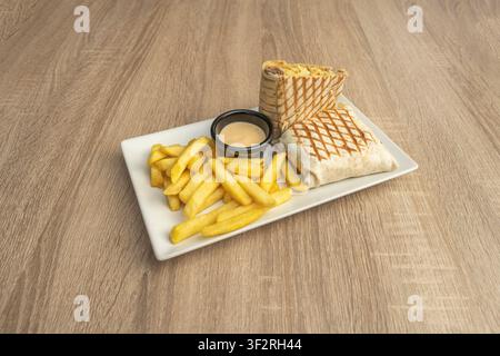 Grilled Beef and Cheese Burrito Wrap Sliced in Half, Served with Fries and Dipping Sauce Stock Photo