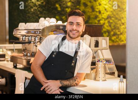 Barista Guy Posing Near Coffee-Machine Standing In Cafe Stock Photo