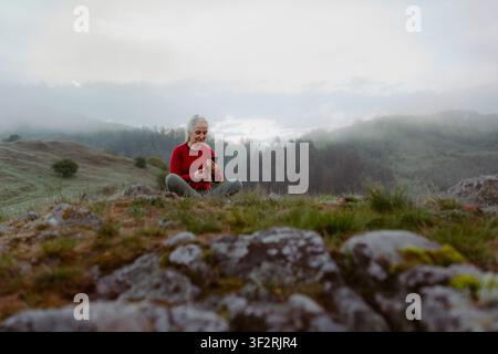 Senior woman checking her phone after exercise in nature on early morning. Stock Photo