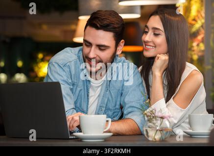 Boyfriend And Girlfriend Using Laptop Having Coffee In Coffeehouse Stock Photo