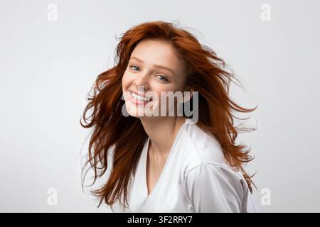 Headshot Of Smiling Red-Haired Young Female Over Gray Background Stock Photo