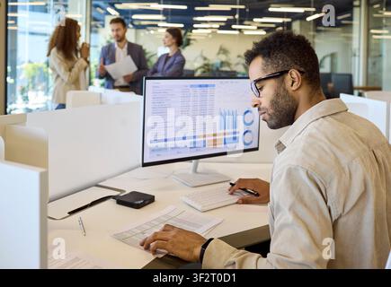 Financial manager analyzing spreadsheet charts on desktop computer in office Stock Photo