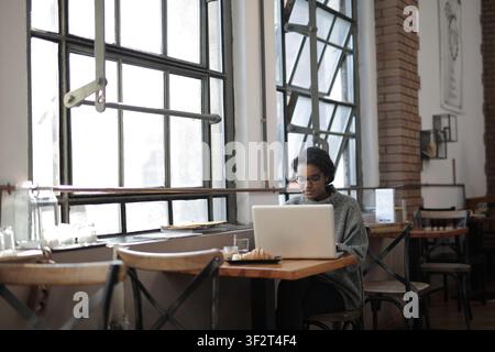 Young black woman works on laptop in cafe Stock Photo