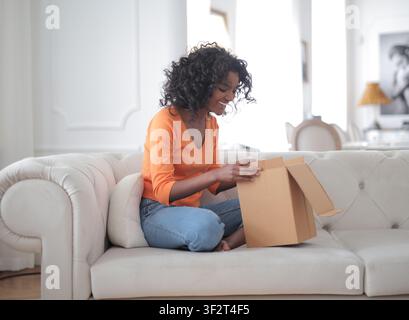 Happy young woman opening a package at home Stock Photo