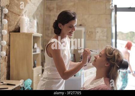 Makeup artist applying eyeshadow to a smiling woman Stock Photo