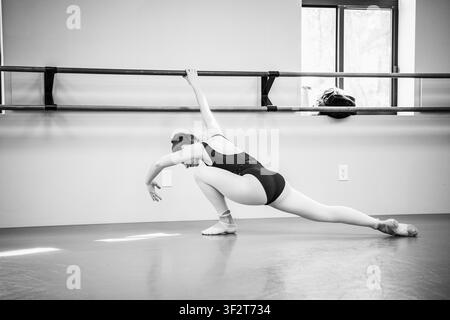 Dancer stretching at barre in black and white studio Stock Photo