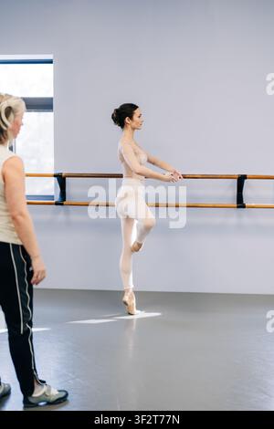 Ballerina practicing ballet at barre with instructor watching Stock Photo