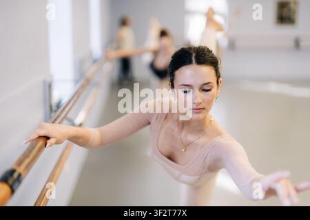 Young ballerina practicing graceful barre exercise in dance studio Stock Photo
