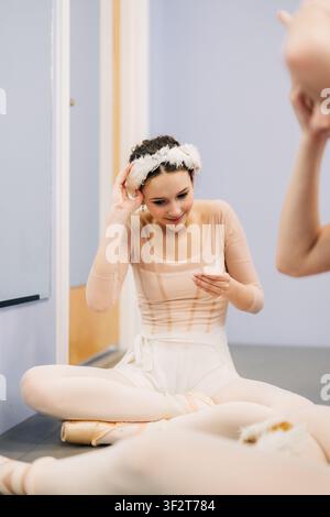 Ballerina adjusting feather headpiece during ballet rehearsal Stock Photo