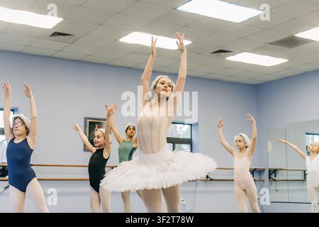 Ballet class practicing synchronized arm positions in dance studio Stock Photo
