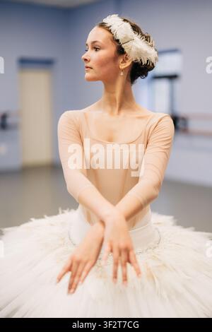 Young ballerina in white tutu practicing graceful ballet pose Stock Photo